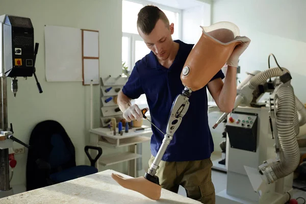 Jeune spécialiste de la production de prothèses assemblant jambe artificielle — Photo