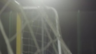 Futbol kalesinde ağdan eğilip rüzgarda savruluyor açık havada futbol sahasında geceleri spot ışıklarıyla.