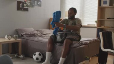 Genç siyahi bir adamın sabah futbol antrenmanı için toplandığı bir fotoğraf.