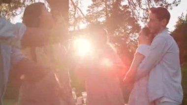 Low angle of young ethnically diverse men and women wearing casual clothes spending summer evening together outdoors dancing and chatting