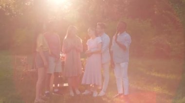 Group of modern multi-ethnic young men and women spending time together during party in park