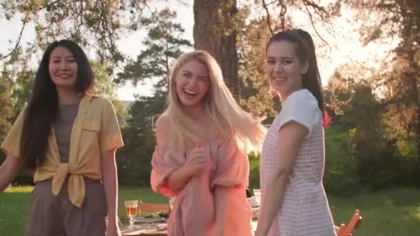 パーティー中に美しい公園で屋外で楽しいダンスをしているスタイリッシュなカジュアルな服を着ている3人の女性の友人のグループ — ストック動画