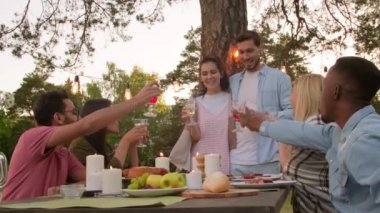 Group of modern multi-ethnic young men and women having fun together in park celebrating something