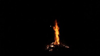 Siyah arkaplandaki büyük şenlik ateşine fırça atan adam ve çocuğun siluetleri. Gerçek alevler. Yanıyorum. Ateşlendi. Gece kamp ateşi. Turuncu renk. Açık hava eğlencesi. Sonbahar bahçe temizliği.