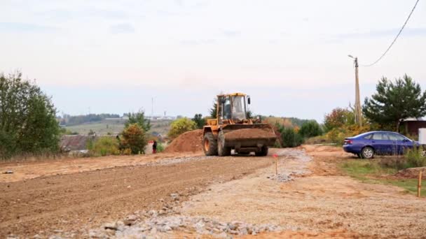 ベラルーシ ミンスク 2021年10月8日 トラクターブルドーザーは土壌の完全なバケツを運びます 接近中だ フロントエンドローダー 道路建設 大規模な掘削機は瓦礫を圧縮する 高速道路の高架化 建築現場 — ストック動画