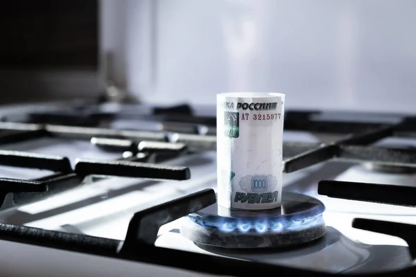 Concept of gas crisis. 1000 russian ruble bank note is burning on a kitchen stove. Cash money. High prices of natural resources. Blue flame. Utility debt. Energy war. Saving home budget. Thousand.