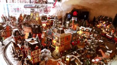 Noel Baba 'yla minyatür festival kasabasının Noel oyuncakları yerleştirilmesi, yeni yıl ağacı, tren, evler, dükkan, hayvanlar ve küçük insanların taşınması. Market vitrini. 1 Aralık 2021 - Minsk, Belarus