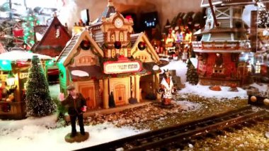 Minyatür kentin Noel oyuncakları, şenlikli tren istasyonu, yeni yıl ağacı, taşınan tren, evler, keçi ve küçük insanlar. Market vitrini. Peri şehri. 1 Aralık 2021 - Minsk, Belarus