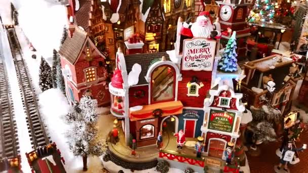Noel Baba, yeni yıl ağacı, tren yolu, dükkan ve taşınan küçük insanlarla dolu küçük bir Noel kasabasının Noel kurulumu. Güzel el yapımı oyuncak şehri olan bir market. 1 Aralık 2021 - Minsk, Belarus — Stok video