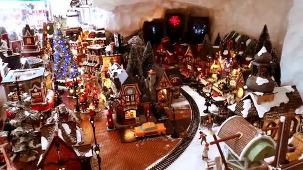 Instalação de brinquedos de Natal da cidade festiva em miniatura com Papai Noel, árvore de Ano Novo, trem de trem em movimento, casas, lojas, animais e pessoas pequenas. Mostra de mercado. 1 de dezembro de 2021 - Minsk, Bielorrússia — Vídeo de Stock