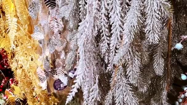 Enfeite de textura diferente. Decoração de Natal de ouro e prata. Brinquedo de Ano Novo e vitrine de loja de grinalda. Ramos de abeto artificial na neve. Fita de folhas brilhantes. 1 de dezembro de 2021 - Minsk, Bielorrússia — Vídeo de Stock