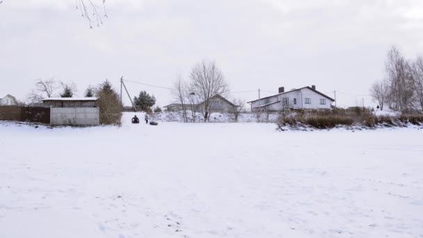 チューブ ライディング チューブ 男は雪の丘を転がっている 屋外の冬の楽しみ 家族のレジャー アクティブウォーク 季節の娯楽 自然を背景に 大きな雪原だ — ストック動画