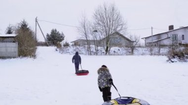 Baba ve oğul kar kaydırağının tepesine boru döşeyecek. Açık havada kış eğlencesi. Aile eğlencesi. Aktif yürüyüş. Mevsimlik eğlence. Doğa geçmişi. Büyük, karlı bir arazi. Küçük çocuk ve adam.
