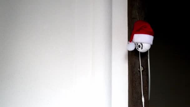 Câmera CCTV branca em chapéu vermelho Papai Noel gira e grava objetos em movimento. Vigilância vídeo ao ar livre. Sistema de segurança. Filmagem. Espaço para cópia. Câmara Web. Controlo nas ruas. Vigilância à distância. Tecnologia inteligente — Vídeo de Stock
