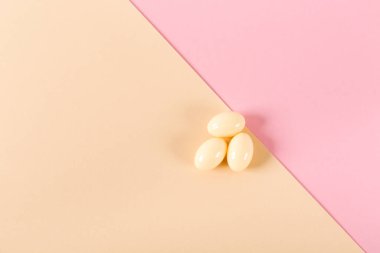 Pembe ve bej arka planda üç tablet. Vajinal antibakteriyel kapsüller. Yakın plan. Kabarma başladı. Uzayı kopyala Tıbbi tedavi. Düz yatıyordu. Model tasarımı. Hiç kimse. Şablon. İlaç..