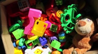 Çeşitli çocuk oyuncaklarıyla dolu bir karton kutu. Plastik renk yapıcı, yumuşak ayı, oyuncak bebek ve diğer eğitici oyuncaklar. Çocukluk konsepti. HD video görüntüleri. Bebek oyunu objeleri. Fakir ailelere bağış