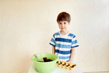 Küçük bir çocuk fidanlar için tohum ekiyor. Bahçıvanlar için hayat biçiyor. İlginç bir aktivite ve çocuk için yararlı bir hobi. Anaokulu eğitimi. İnsan ve doğa. Bitki yetiştiriyorum. Çiftçilik. Boşluğu kopyala