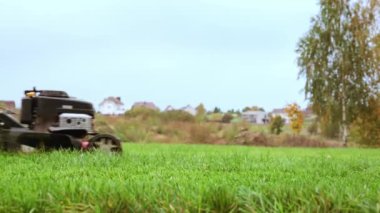 Bahçe kırmızısı çim biçme makinesi. Çim biçen işçilerin yan görüş açısı düşük. Yeşil çim kesiminin etkinlik detayları. Peyzaj bakımı. Bahçe bakımı. Yakın plan. Bahçıvan servisi. Beton kaldırım yolu