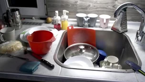 4K. A pile of dirty dishes on the table and in the kitchen sink. Plates in leftover food. Routine homework. Cleaning concept after guests. A very unkempt house. Nobody. Sloppy look. Video footage — Stockvideo