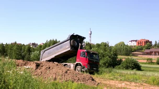 2021年6月19日-ベラルーシのミンスク。1台の大型ダンプトラックが建設現場に土壌を持ち込み、それをアンロードします。荷を背負って。夏の建物の季節。地球の輸送だ。大きな車だ。共通ビュー — ストック動画