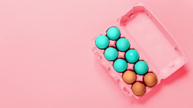 Paskalya tatili. Pembe arka planda boyayı maviye çeviren tavuk yumurtalarının paketlenmesi. Uzayı kopyala Pankart. Video görüntüleri. Hediye. Din kavramı. Tasarımı taklit et. Minimalist modern tarz. Şenlikli yemek.