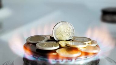 Gaz krizi kavramı. Mutfak ocağında 2 Euro 'luk madeni para yanıyor ve benzin bittiğinde düşüyor. Doğal kaynakların yüksek fiyatları. Ateş alevi. Kamu borcu. Enerji savaşı. Ev bütçesini biriktiriyorum. Finans