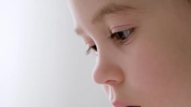 5 yaşındaki küçük bir çocuğun yüzü son derece yakın çekim. Yan görüş. Çocuk yorgun, uyumak istiyor. Kurumuş gergin gözler. Uzayı kopyala Beyaz arka plan. Oftalmoloji. Bebek görüşü. Dikkatli bak ve çalış.