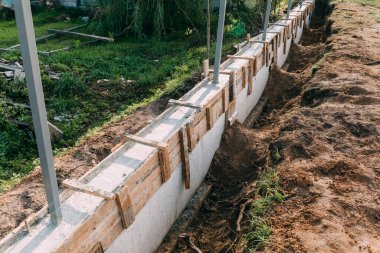 Metal takviyeli ahşap döşeme, beton dökme ve bir bina ya da çit için sağlam bir temel oluşturma. İnşaat süreci. İstinat duvarını inşa ediyorum. Yan görüş. Hiç kimse. Boşluğu kopyala