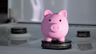 Domuz kumbarası mutfak ocağının üstünde duruyor. Alternatif tasarruf parası kavramı. Evin arka planında para kutusunda para var. Gaz kaynakları için yüksek fiyat. Gelecek için yatırım