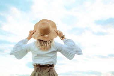 Kafkasyalı genç bir kız ya da kadının üzerinde saten kurdele olan hasır şapka. Arka plan yakın plan. Şık bir aksesuar. Yaz yaşam tarzı. Özgürlük kavramı. Kıyafet elemanı. Moda. Doğal arka plan. Zarif stil.