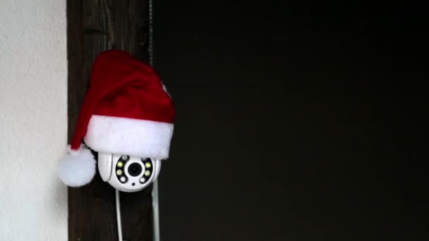 Caméra CCTV blanche en chapeau rouge du Père Noël tourne et enregistre les objets en mouvement. Surveillance vidéo extérieure. Système de sécurité. Des images. Espace de copie. Web cam. Contrôle de rue Web. Montre de distance. Technologie intelligente — Video