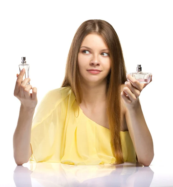 Moda jovem mulher escolhendo um perfume no fundo branco — Fotografia de Stock