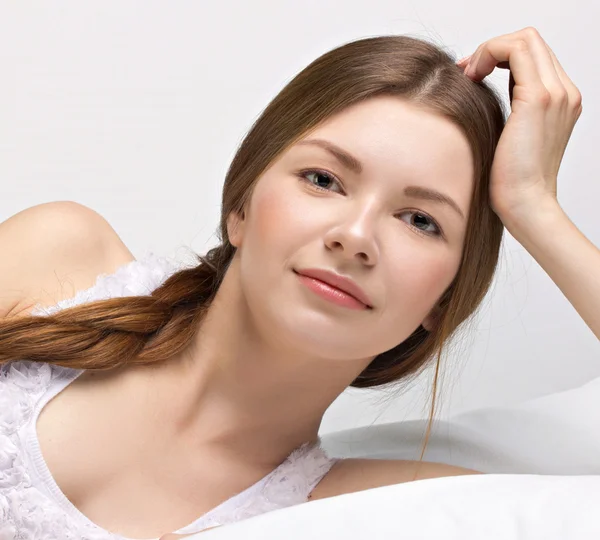 Mooie jonge vrouw in een bed — Stockfoto