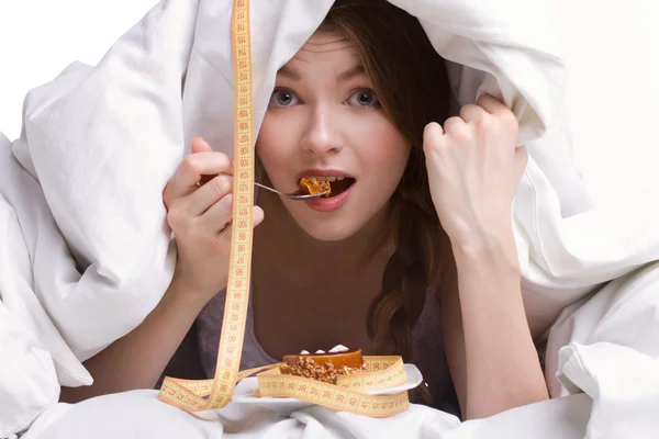 Menina bonita comendo sob cobertura — Fotografia de Stock