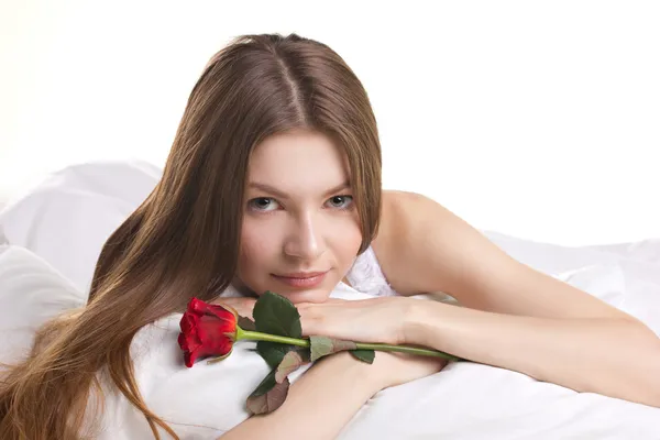 Femeie frumoasă cu trandafir într-un pat — Fotografie, imagine de stoc