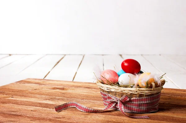 Huevos coloridos y plumas en cesta — Foto de Stock