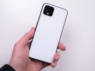 White smartphone in hand on a white background top view