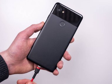 Akıllı telefon, beyaz arka plandaki şarj cihazına bağlıdır. Şarjı bitti. Şarjım bitiyor. Akıllı telefon şarj aletinin fişini tak.