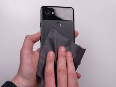 Beyaz arka plan görünümlü mikrofiber peçeteyle çamurdan silinmiş akıllı telefon.