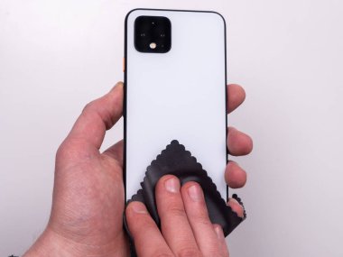 Beyaz arka plan görünümlü mikrofiber peçeteyle çamurdan silinmiş akıllı telefon.