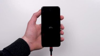 Akıllı telefon, beyaz arka plandaki şarj cihazına bağlıdır. Şarjı bitti. Şarjım bitiyor. Akıllı telefon şarj aletinin fişini tak.