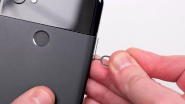 SIM kart için SIM tepsiyi beyaz arkaplanda siyah akıllı telefon yakın plan görüntüsüne yerleştir