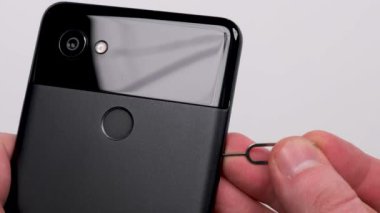 SIM kart için SIM tepsiyi beyaz arkaplanda siyah akıllı telefon yakın plan görüntüsüne yerleştir