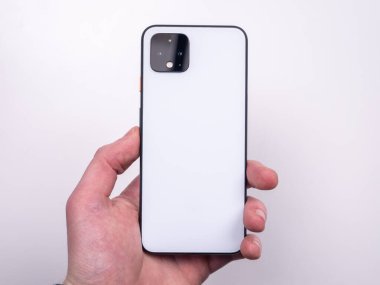 White smartphone in hand on a white background top view