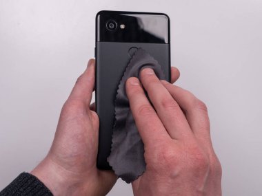 Beyaz arka plan görünümlü mikrofiber peçeteyle çamurdan silinmiş akıllı telefon.