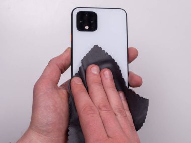 Beyaz arka plan görünümlü mikrofiber peçeteyle çamurdan silinmiş akıllı telefon.