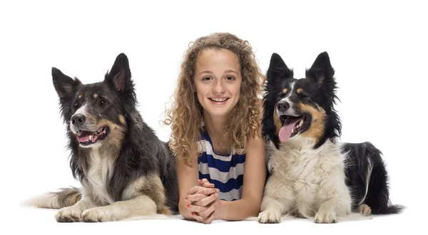 Giovane ragazza sdraiata tra due Border Collie sullo sfondo bianco — Foto Stock