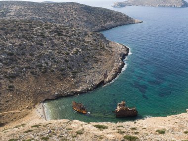 Yaz tatillerinde Amorgos adasındaki Batık Olympia teknesinin sahildeki kayalık bölgede, sahildeki insanlar, Cyclades, Yunanistan 'daki insansız hava aracı görüntüsü. Seyahat arkaplanı