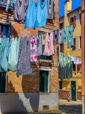 İtalya 'da Venedik' in küçük geleneksel bir caddesinde asılmış kıyafetlerin altında yürüyen bir kadın. Seyahat arkaplanı