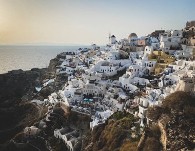 Ege Denizi 'ndeki Santorini adasındaki geleneksel beyaz mimari ve yel değirmenleriyle Oia köyünün panoramik manzarası, seyahat geçmişi, Santorini, Thera, Yunanistan